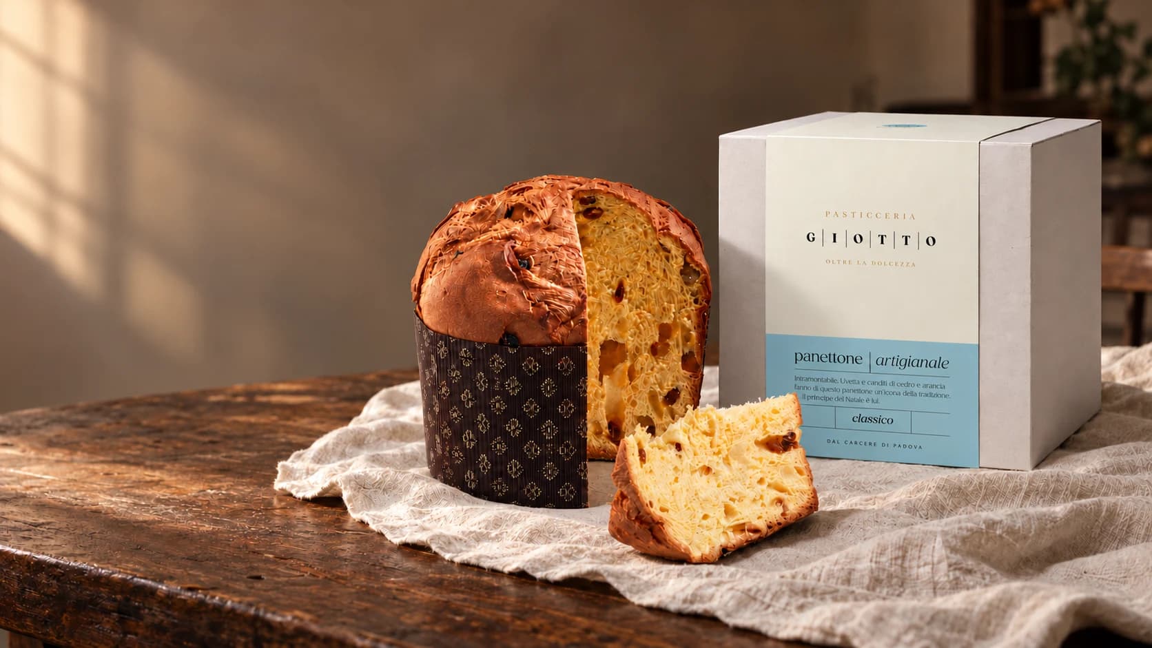 Le panettone artisanal Giotto Classico, une part coupée, à côté de son coffret, sur une table en bois.